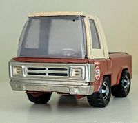 Front angle view of Buddy L pressed steel vintage pickup truck showing brown body, tan cab, clear windshield and silver grill.