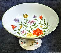 Top angled view showing overall floral decorated pedestal compote bowl with green trim on rim and base.