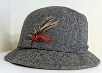 Side angled view of vintage tweed fedora hat with feathers showing texture and feather detailing.