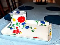 White vinyl serving tray and matching ice bucket with colorful flowers placed on a light blue tablecloth