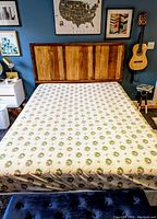 Full view of the flat sheet spread over bed with rustic wooden headboard, showing overall size and pattern.