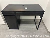 Full view of the black wood grain small task desk showing drawer and cabinet on the left and open metal frame leg on the right.