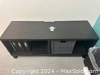 Top view of the black wood shelf showing compartments and basket inside the right middle section with some binders in left section.