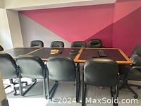 Conference room table with 10 black leather chairs arranged around it, showing full length and width of table and chair design.