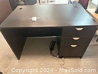 Full view of the dark wood desk showing top surface, leg space, and three drawers on the right side.