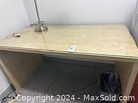 Top view of the light wood grain small task table or desk with a silver task lamp on top and trash bin beneath.