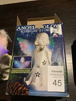 Original packaging box of the Angel Glow Sculpture Illuminate showing the angel figurine with glowing wings.