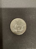 Photo of the Olympic emblem side with '5 Dollars' and 1976 inscription on the coin.