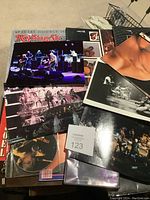 Photo showing a Rolling Stone special double issue magazine, several large concert photographs, and a music CD.