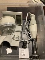 Photo of the electric hand mixer with cord, mixing bowl attachment, and organizer stand inside a plastic bin.