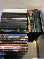Photo showing a pile of DVDs including Jackass box set and titles like U2 Rattle and Hum, American Horror Story, Serenity, and more.