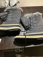 Side view of gray Outbound men's winter boots with black rubber soles and faux fur lining.
