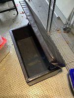 Open view of the rectangular padded storage chest showing the black interior storage compartment and hinged lid upholstered in black faux leather.