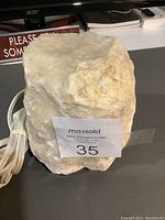 Front view of the small Himalayan salt lamp with attached white electrical cord and MaxSold auction label on it.