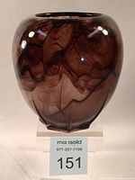 Front view of bulbous violet glass vase with brown streaked pattern on a clear base.