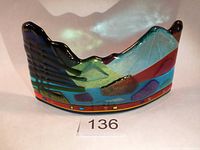 Front view showing colorful fused glass landscape sculpture with stylized mountain peaks and trees, and a red base with small dichroic glass squares.