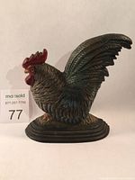 Side view of black cast iron hen door stop highlighting its shape and red comb.