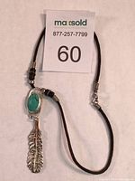 Full view of the Chickasaw turquoise and sterling necklace with cloth cord and accents.