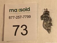 Photo showing full pendant beside a sale identifier card for scale.