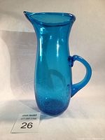 Full view of the blue glass pitcher showing its overall shape and handle.