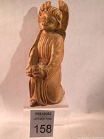 Frontal view of the hand carved wooden angel figurine showing detailed face, hands and robe folds.