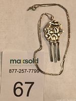 Sterling silver necklace with distinctive handcrafted pendant showing textured and faceted design with three dangles representing paddles and symbolic shapes of hills and rivers. The 19" box chain accompanies the pendant.