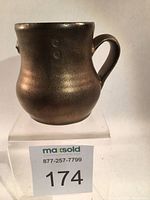 Front and side view of the metallic bronze ceramic coffee mug showing the shape and glaze finish