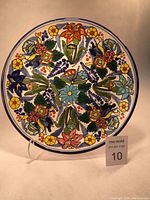 Front view of large round Talavera pottery platter showing vibrant flower patterns and blue rim.