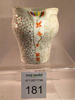 Front view of porcelain yunomi showing hand-carved floral and geometric patterns, colorful oxide decoration including red dots and orange flowers, and a small rainbow motif near the lip.