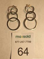 Both sterling silver linked hoops post earrings displayed flat on a beige surface, showing front view with textured circular hoops and post backs.