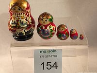 Five vintage Matryoshka dolls of varying sizes arranged in descending order on a clear stand showing overall set condition and detail