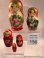 Front view of all 5 vintage nesting dolls in descending size order showing their detailed floral motifs and painted faces.
