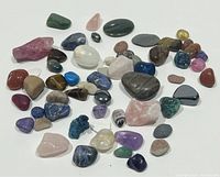 Top view of the assorted polished stones with various colors, sizes, and shapes spread out on a white background.