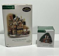 Two boxed pieces from Department 56 Dickens Village Series, the lighted stained glass shop and the glass artisan accessory boxed separately.