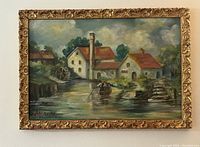 Full view of the framed oil painting depicting a riverside scene with buildings, water wheel, and rowboat.