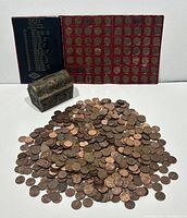 Overview of the lot showing loose pennies pile, metal chest, and penny folio with coin slots