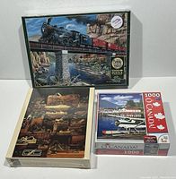 Photo showing all three sealed puzzle boxes: Cobble Hill Steam Train over Bridge, Collection of Planes aviation workshop scene, and O Canada floatplane and marina scene.