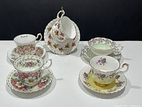 Front and top view of 5 Royal Albert bone china teacup and saucer sets with floral patterns, showing diverse colors and gold trim details
