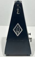 Front view of the black Wittner metronome with logo and winding key on the side.
