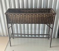Front view of the wicker raised garden bed/plant stand showing woven wicker rectangular frame and sturdy legs.