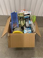Box packed with various personal care and household items, viewed from the front.