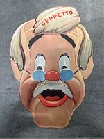 Front view of the colorful Geppetto paper mask with detailed facial features and 'GEPPETTO' text on headband.