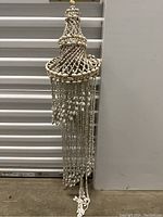 Full view of the seashell hanging decor showing its length and shape against a white background.