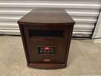 Front view of Trumann heater showing digital temperature reading 63, control buttons, and vent grill in wood-finished casing