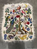 Full view of rectangular embroidered tapestry showing motif and fringe