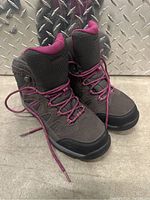 Pair of black/dark gray women's hiking boots with purple lining and laces, viewed from front side angle.