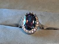 Close-up photo of the sterling silver ring with an oval mystic topaz center stone surrounded by smaller clear stones.