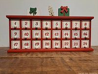 Front view of the advent calendar cubby showing all 24 numbered drawers and top decorations.