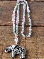 Full view of the gemstone bead necklace with the elephant pendant on a wooden surface.