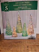 Front view of the set of 5 LED glass trees in original packaging showing the varied sizes and colors
